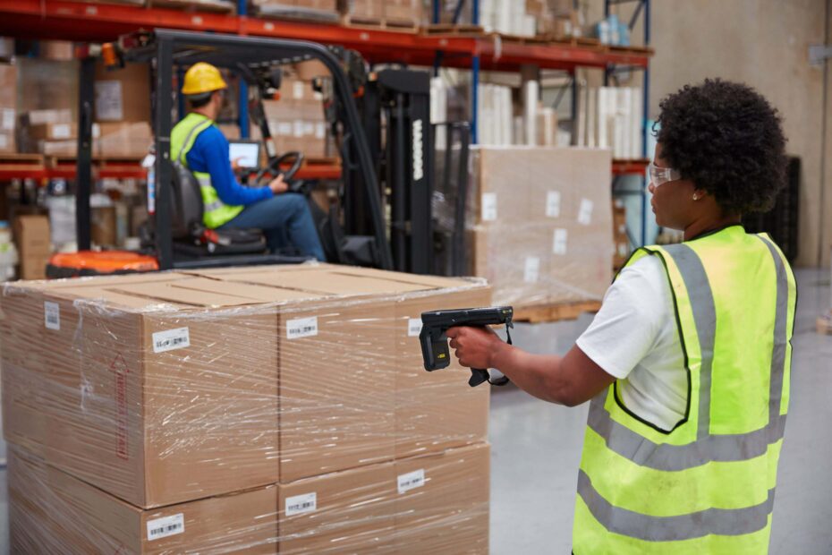 Operador utilizando o coletor de dados Zebra MC3300RFD para leitura rápida de tags RFID em ambiente de armazém logístico, garantindo rastreabilidade.